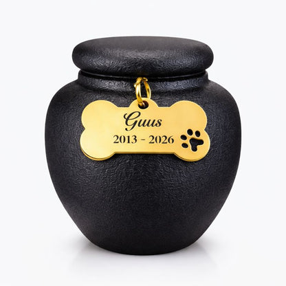 Zwarte keramische mini dierenurn met matte afwerking, ronde vorm en deksel, voorzien van gouden pootafdruk en engelenvleugel.